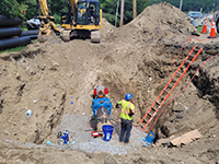 Workers dig to access the water main with the help of a backhoe.